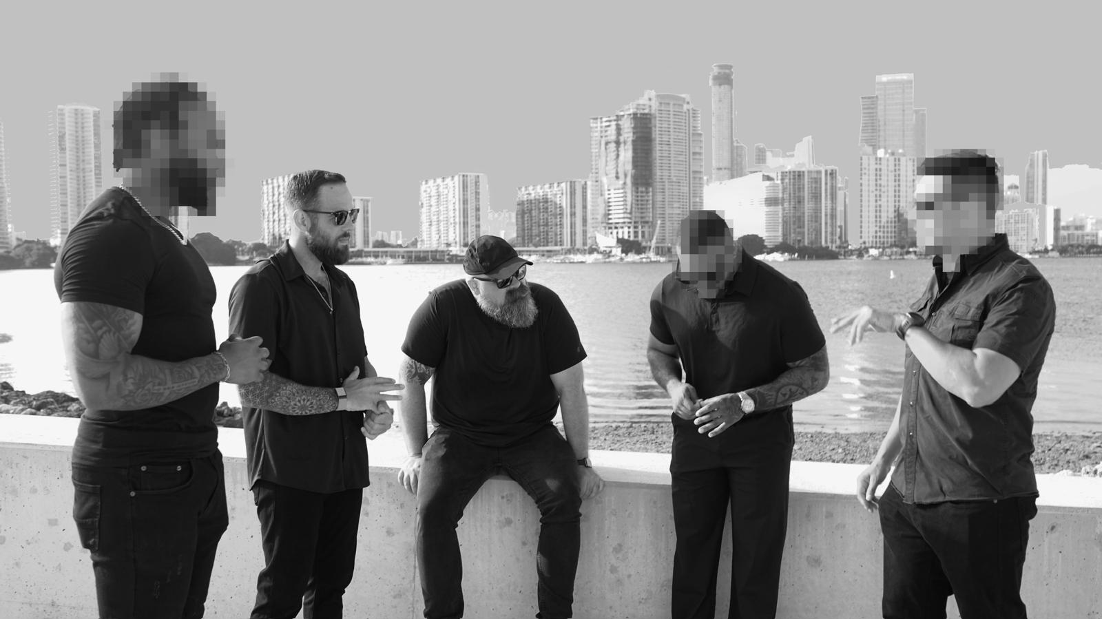 Broward Private Investigations team at Biscayne Bay wall with the Miami skyline behind them — operator identities redacted for client confidentiality